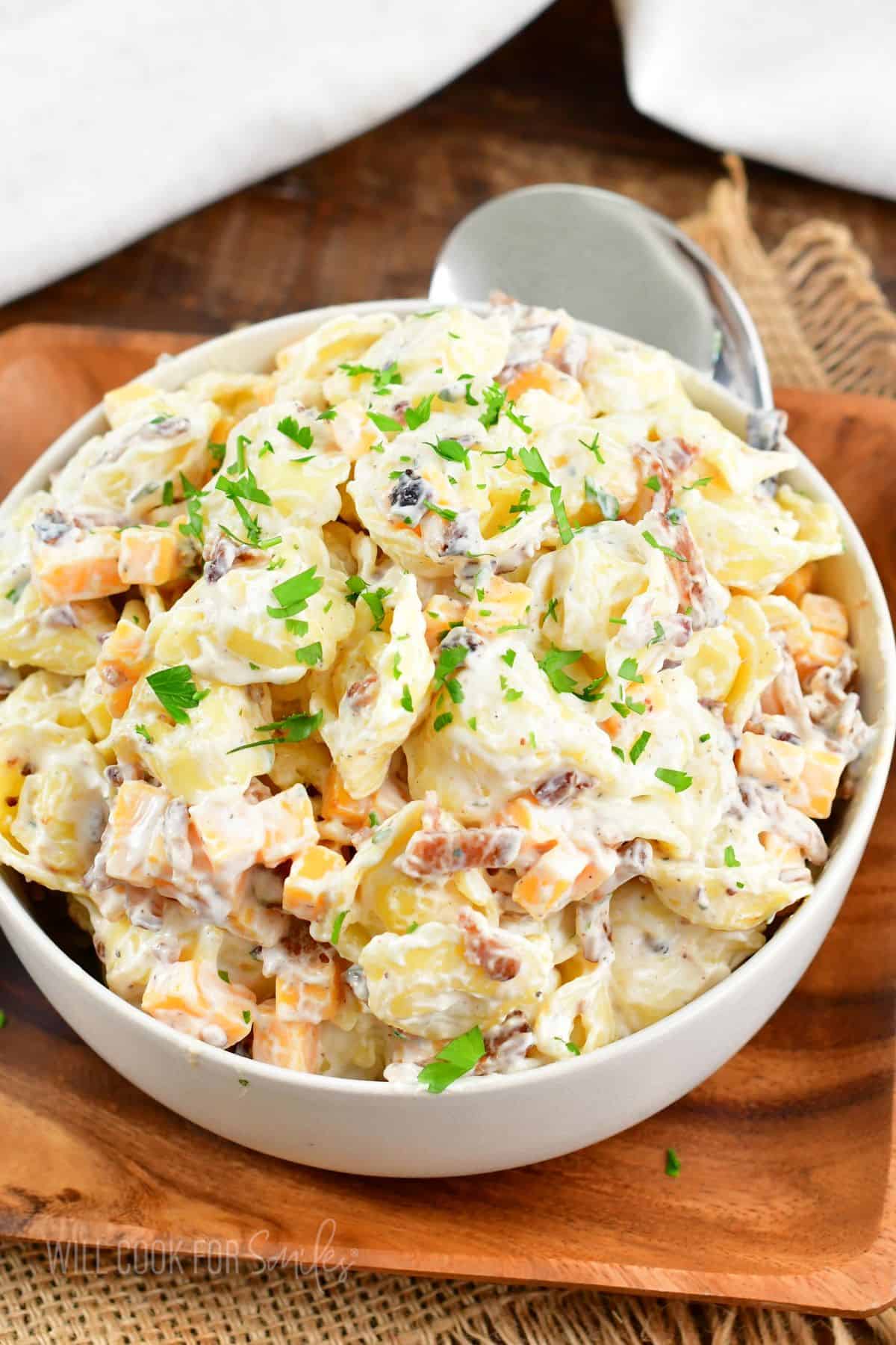 a white bowl is filled with cheddar bacon ranch tortellini salad