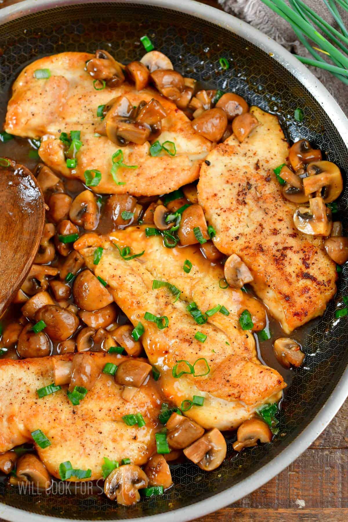 four chicken cutlets in the pan with mushrooms and marsala sauce.