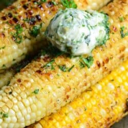 garlic herb butter is placed on top of grilled corn on the cob