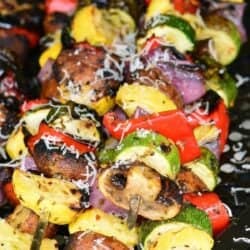 five long skewers with mixed Italian grilled vegetables on them.