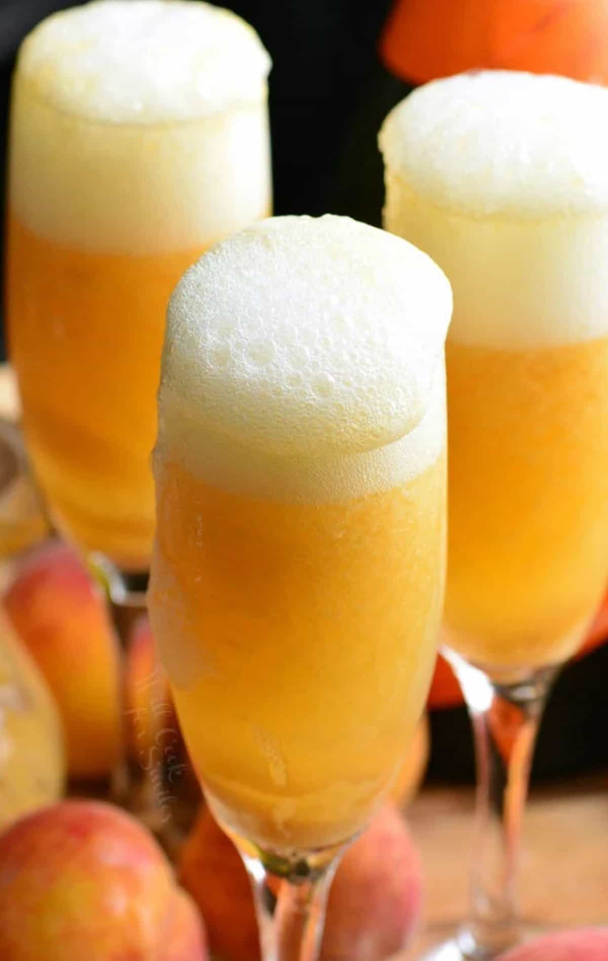 Three glasses are filled with bubbling peach bellinis. 