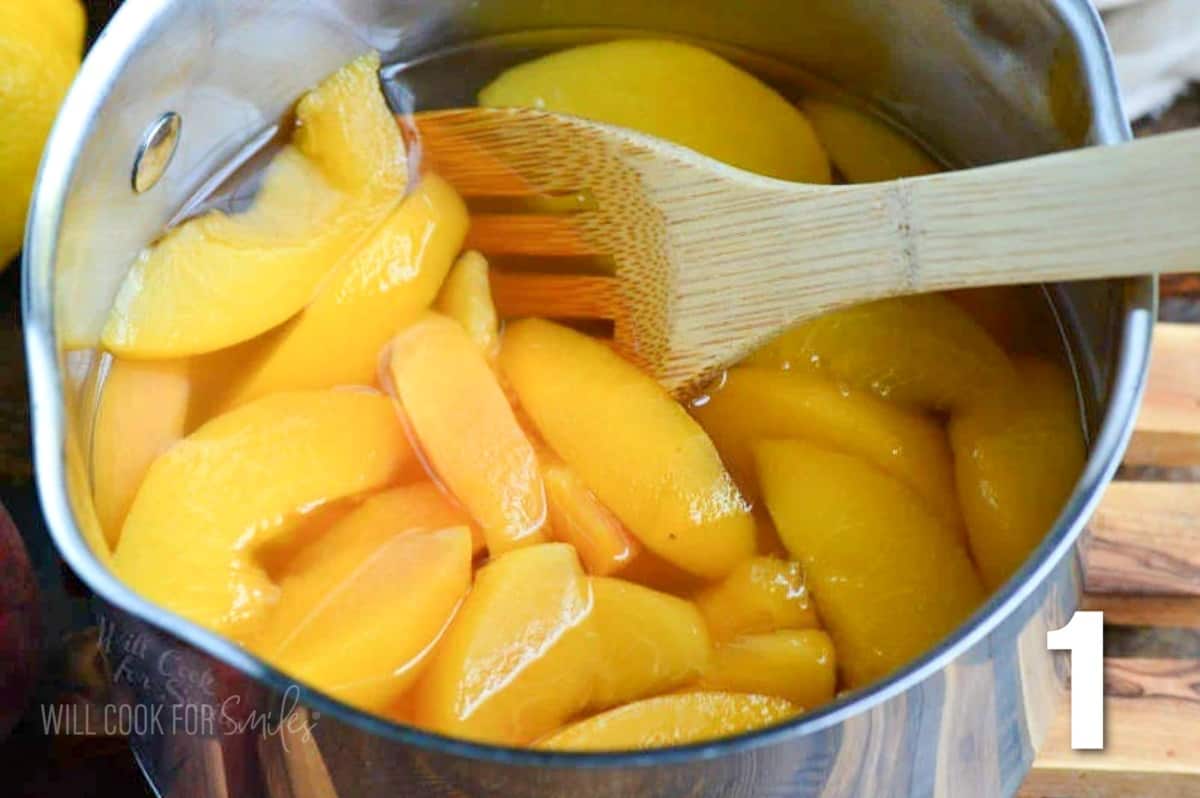 stirring cooked peaches in syrup in a metal pot.