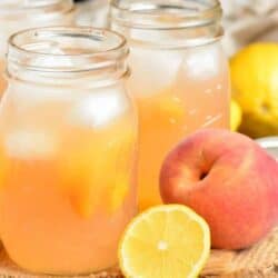 peach lemonade in mason jars with some peaches around.