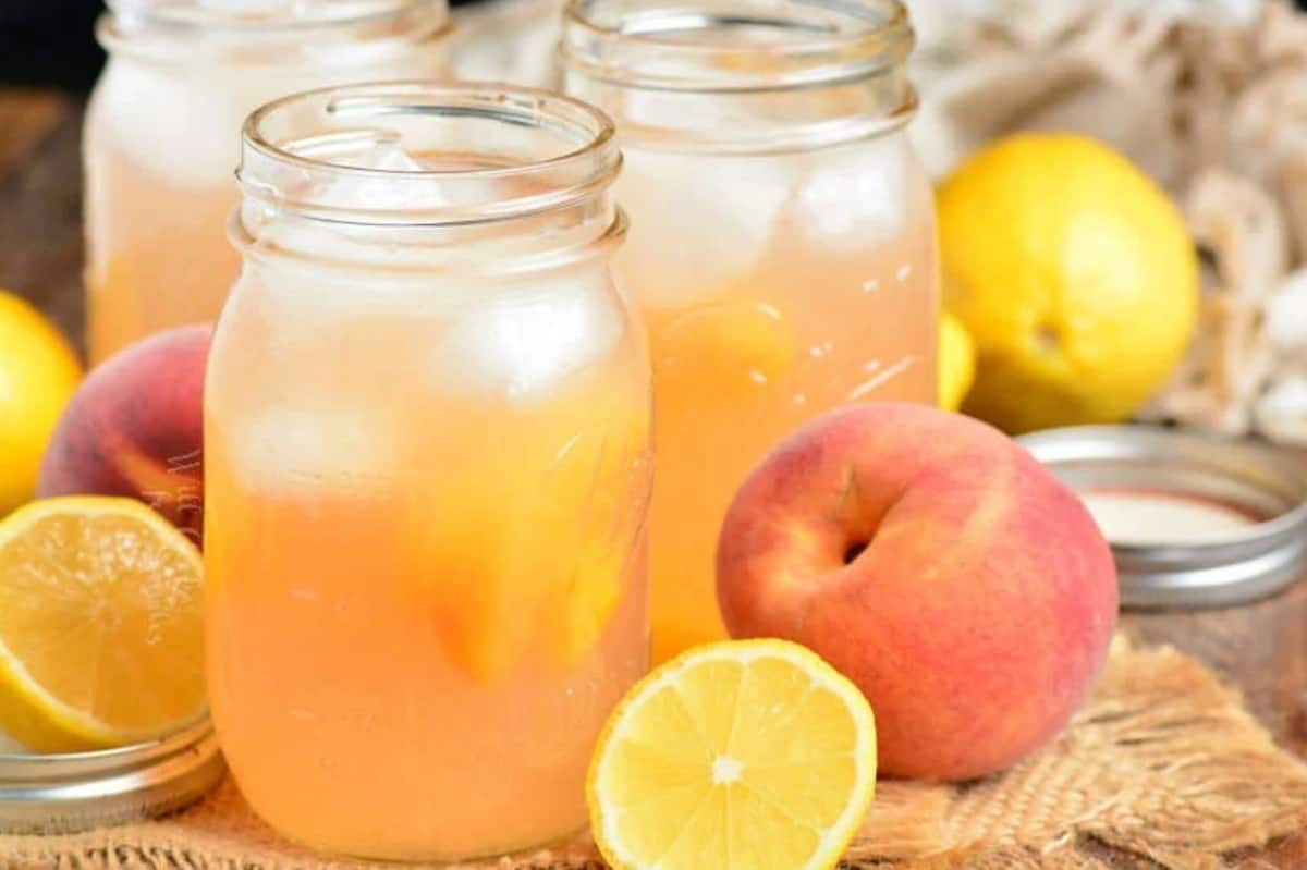 peach lemonade in mason jars with some peaches around.