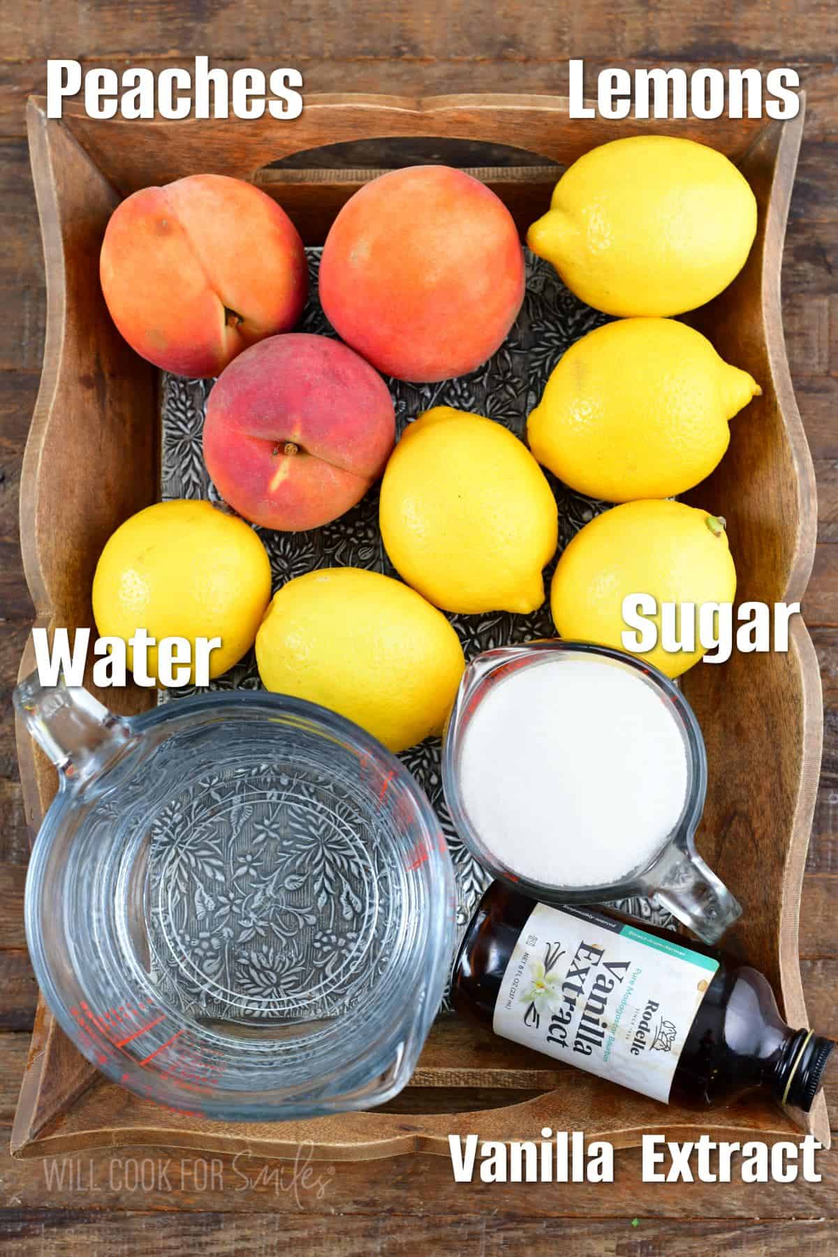 labeled ingredients to make peach lemonade on w wooden tray.