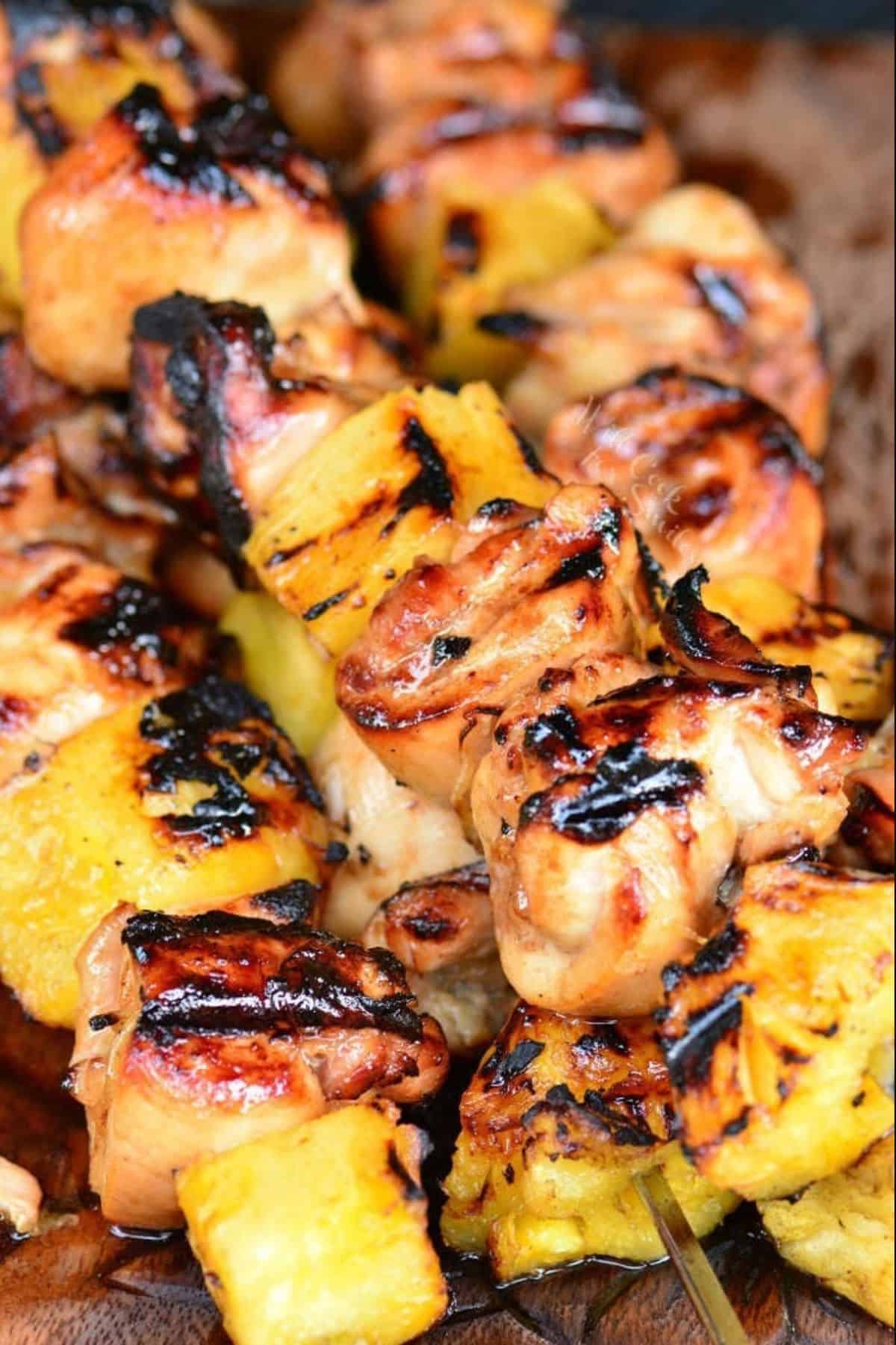 pineapple chicken kebobs are placed in a small pile on a wooden surface
