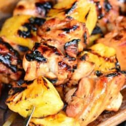 several pineapple chicken kebabs on skewers stacked on top of each other.