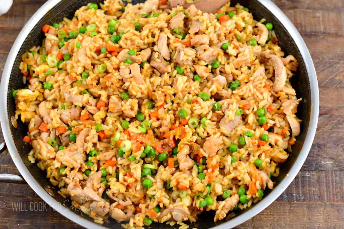 chicken fried rice in a large cooking pan on wooden board.