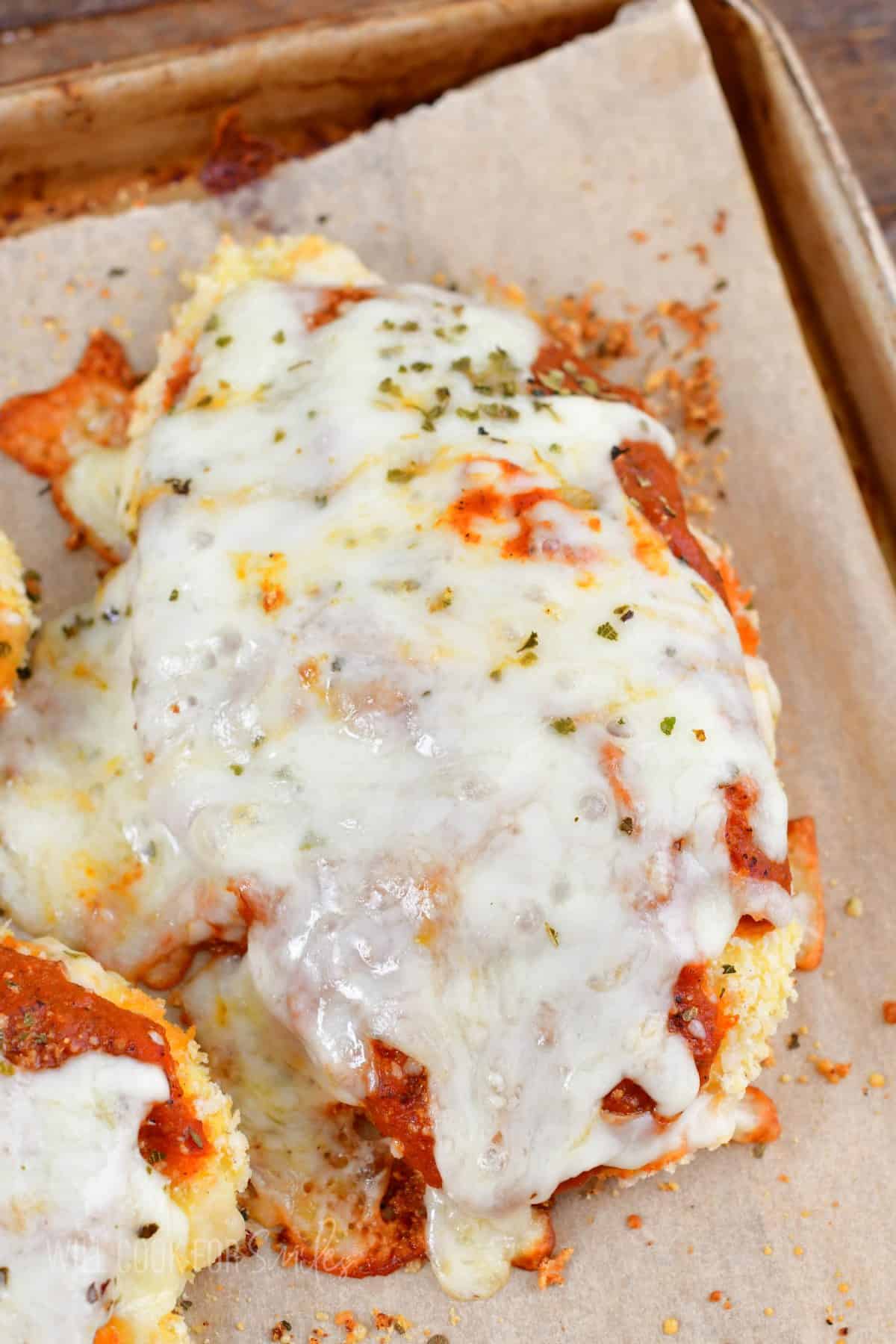 closeup of one chicken parmesan piece on a baking cheese.