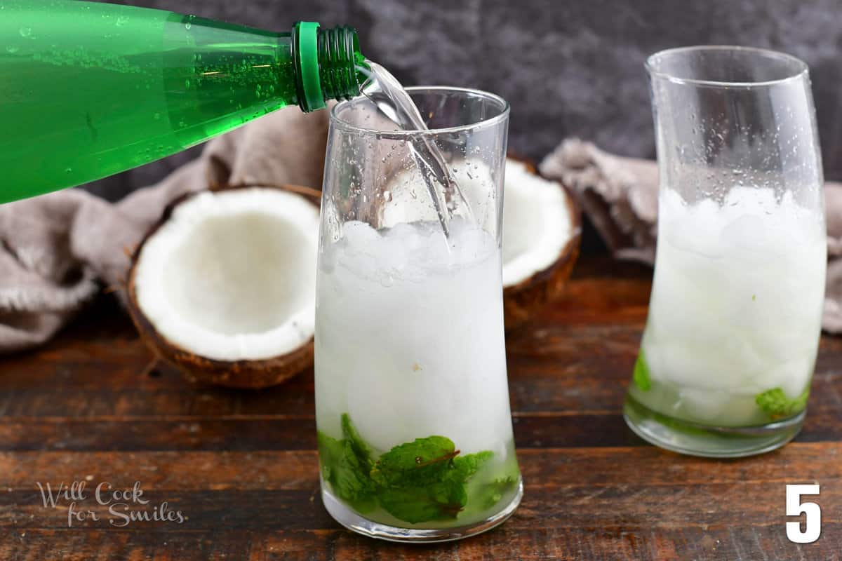 adding soda water to the glass with ice and mint mix.