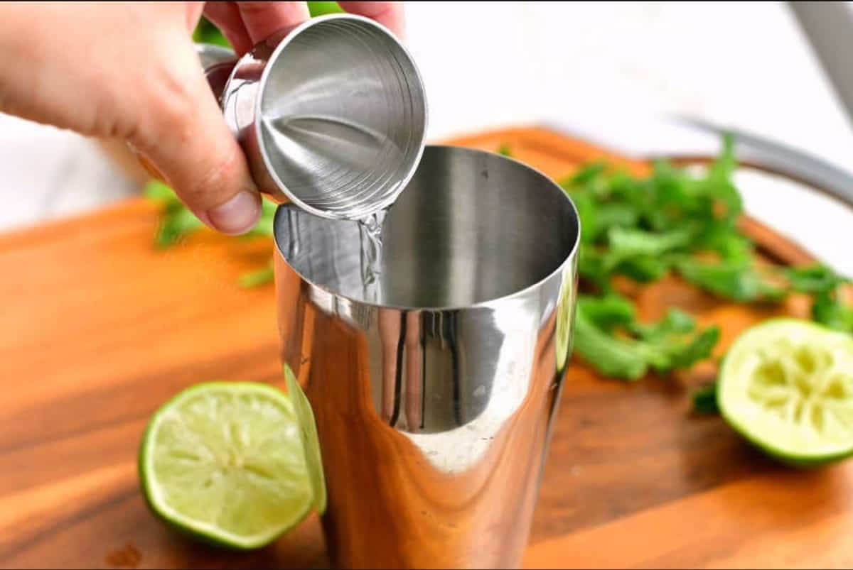 adding rum to the silver cocktail shaker.