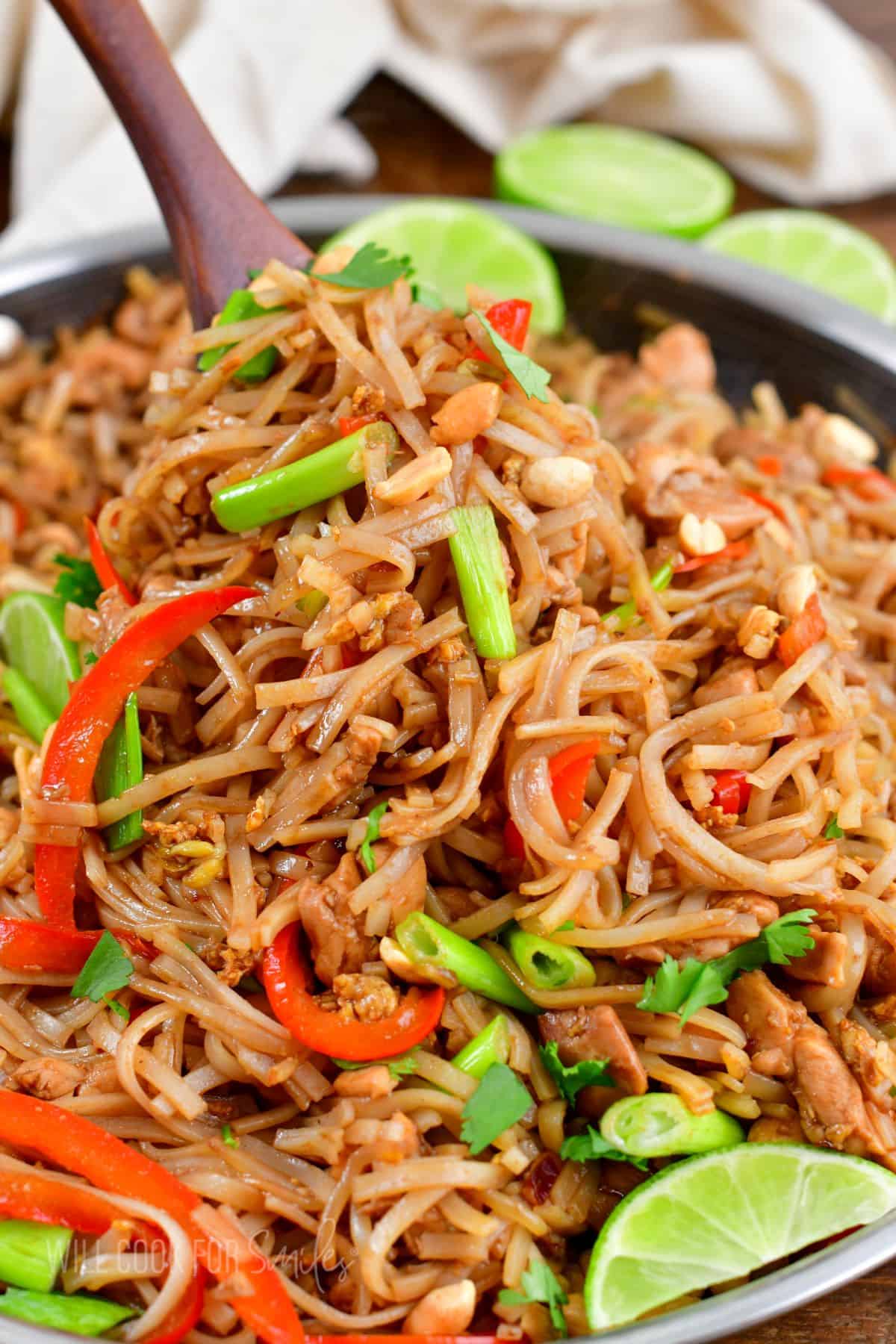 Scooping out a big serving of Pad Thai noodles from the pan.