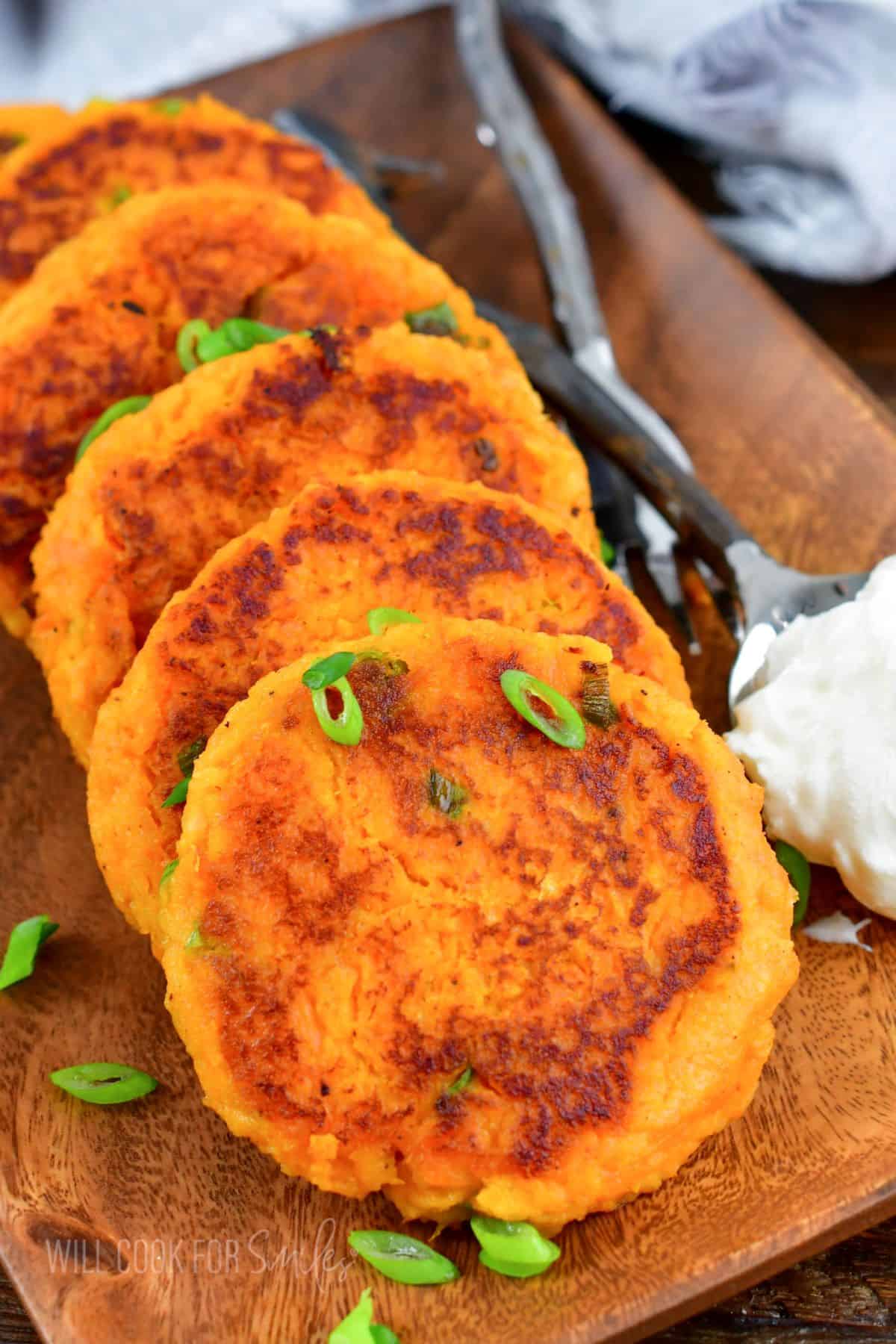 A batch of sweet potato cakes are garnished with green onions. 