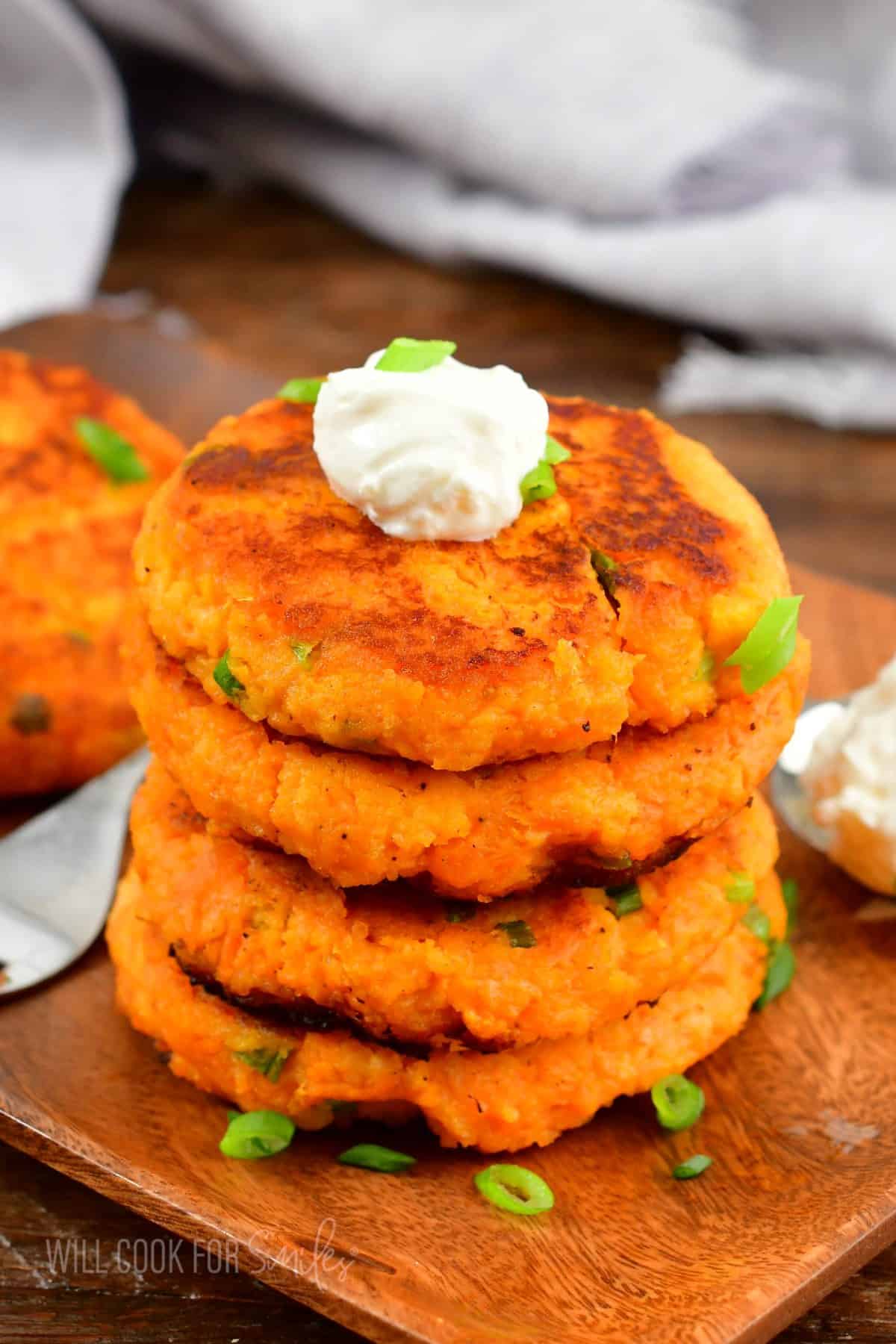 A stack of sweet potato cakes is topped with a dollop of sour cream. 