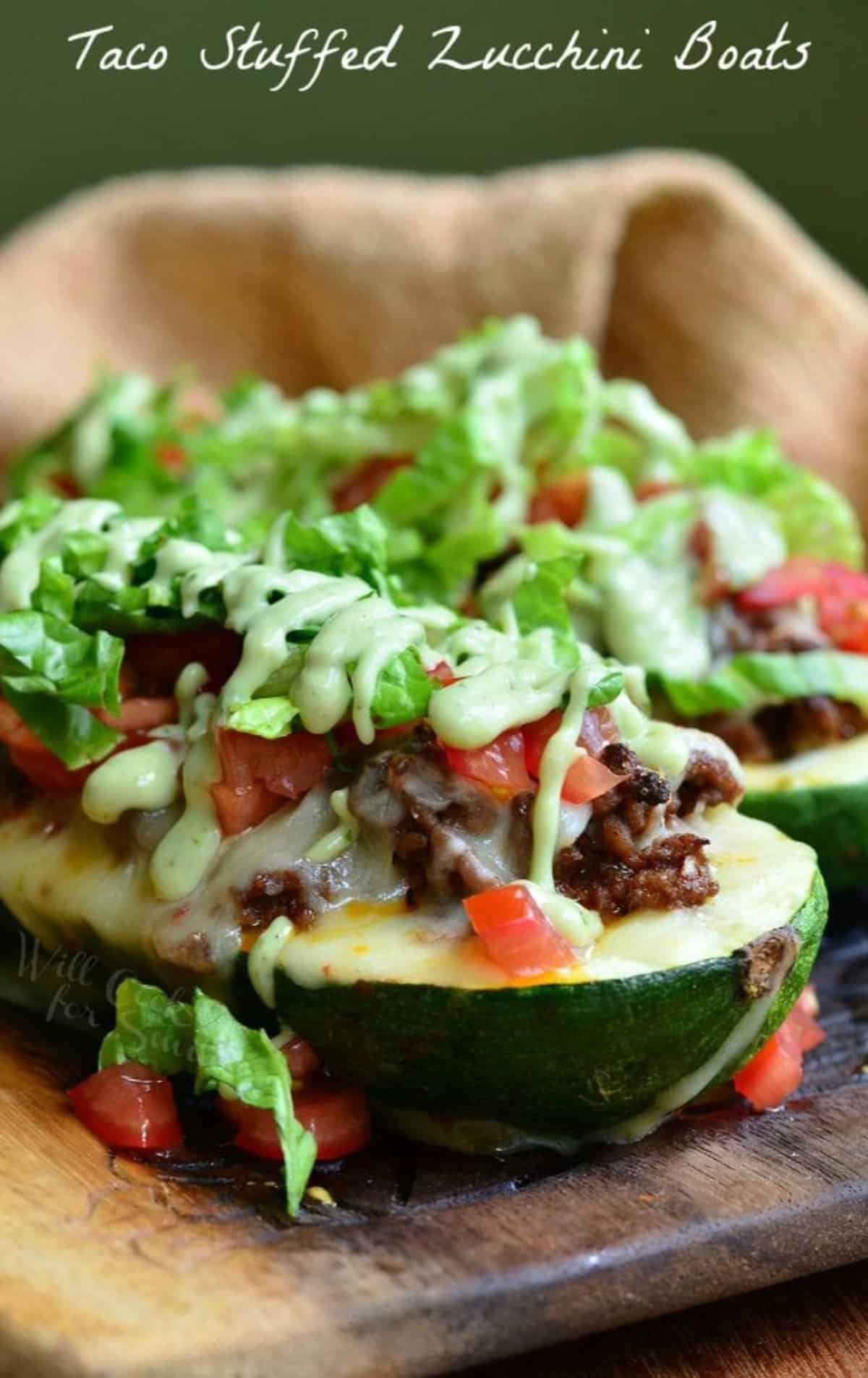 large zucchini boat stuffed with beef and topped with lettuce, tomatoes, and dressing.