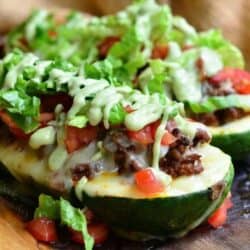 two stuffed zucchini boats with beef, lettuce, and avocado dressing.
