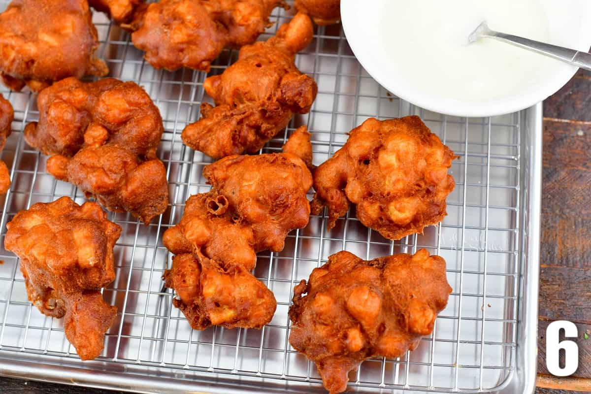 fried apple fritters on the wire rack and icing.