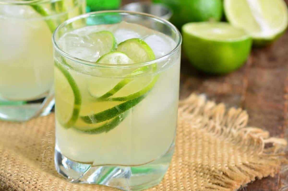 caipirinha in a short glass with ice and lemons in the glass and lemons in the background.