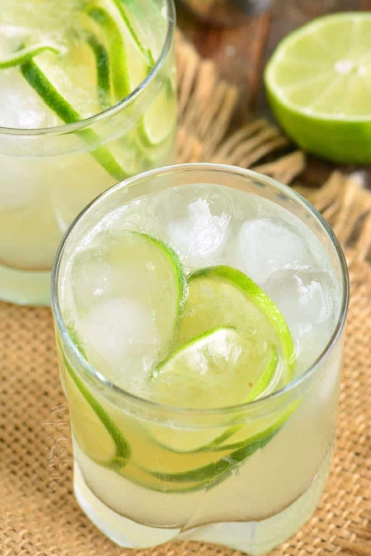 caipirinha in a short glass with ice and lemons on a brown table cloth.