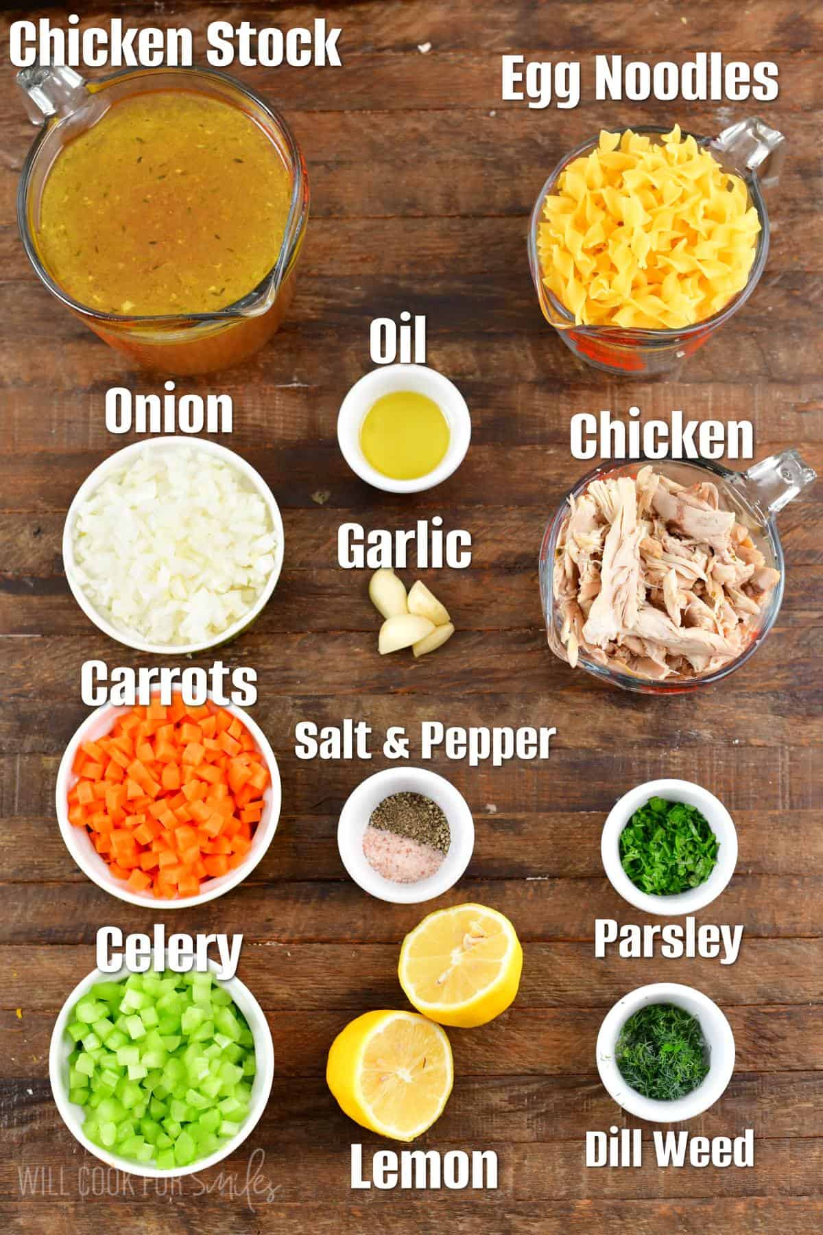 Labeled ingredients for chicken noodle soup on a wood surface.