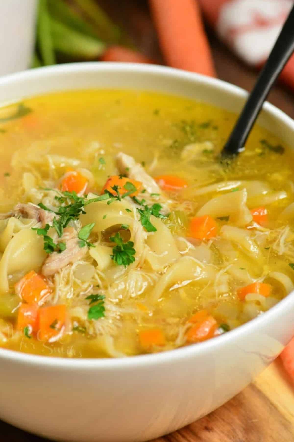 bowl of chicken noodle soup with a spoon laying in the bowl.