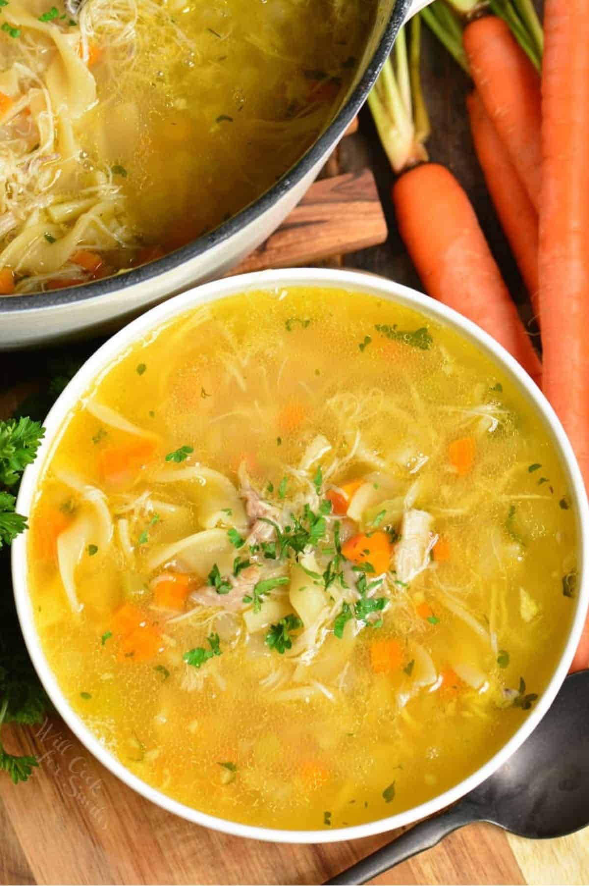 bowl of chicken noodle soup on a wood surface.