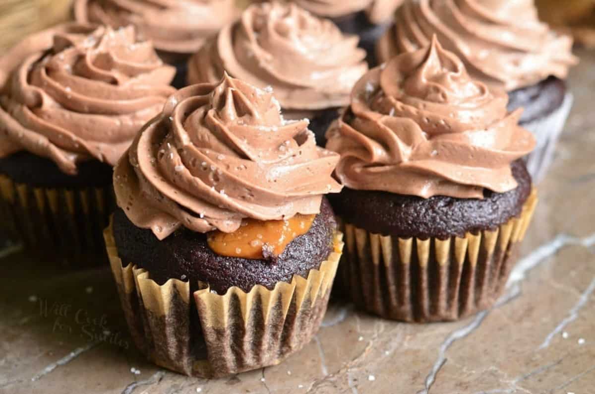 several Chocolate cupcake with salted dulce de leche filling sitting on a stone counter close together.