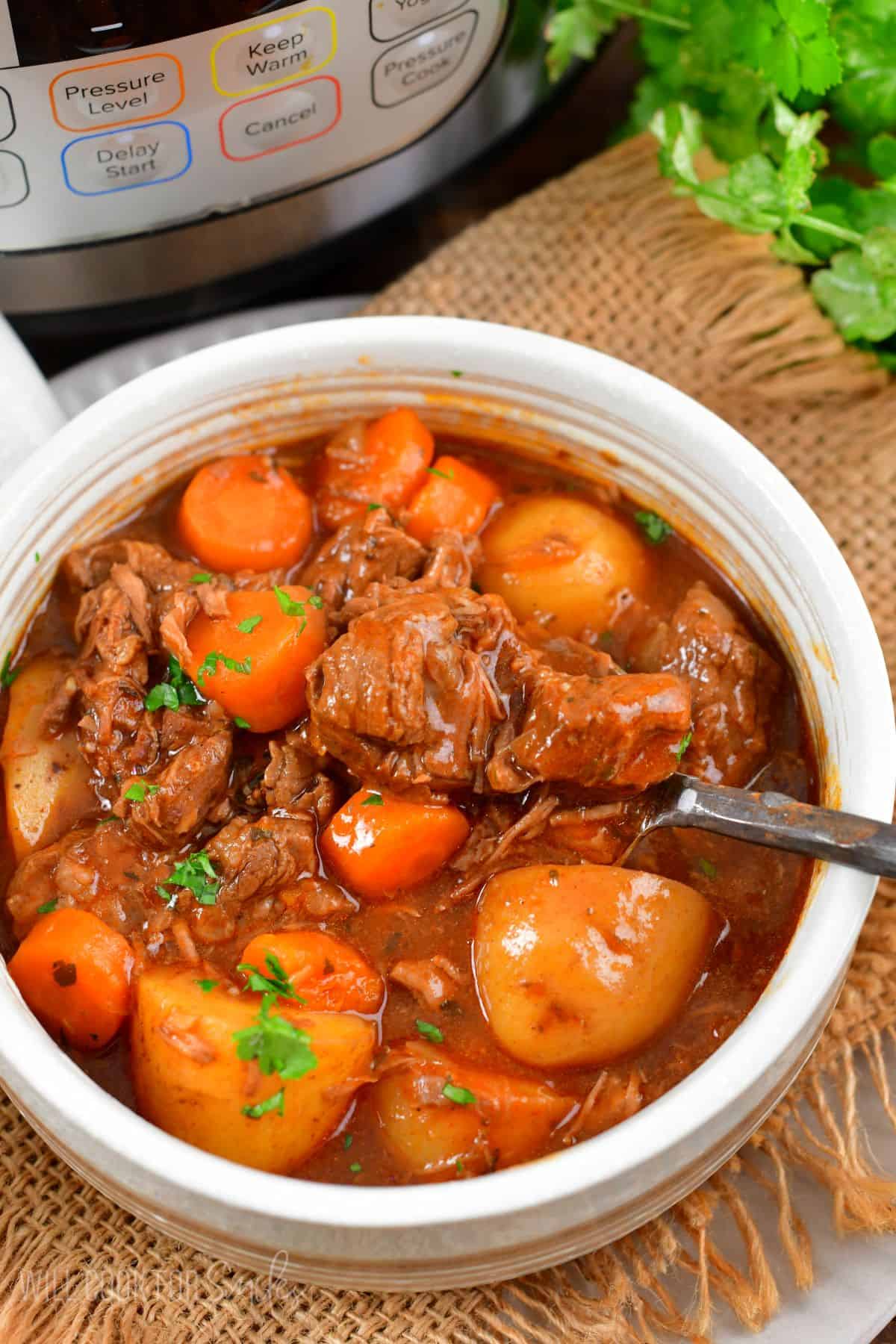 beef strew in a bowl with the fork scooping some out.