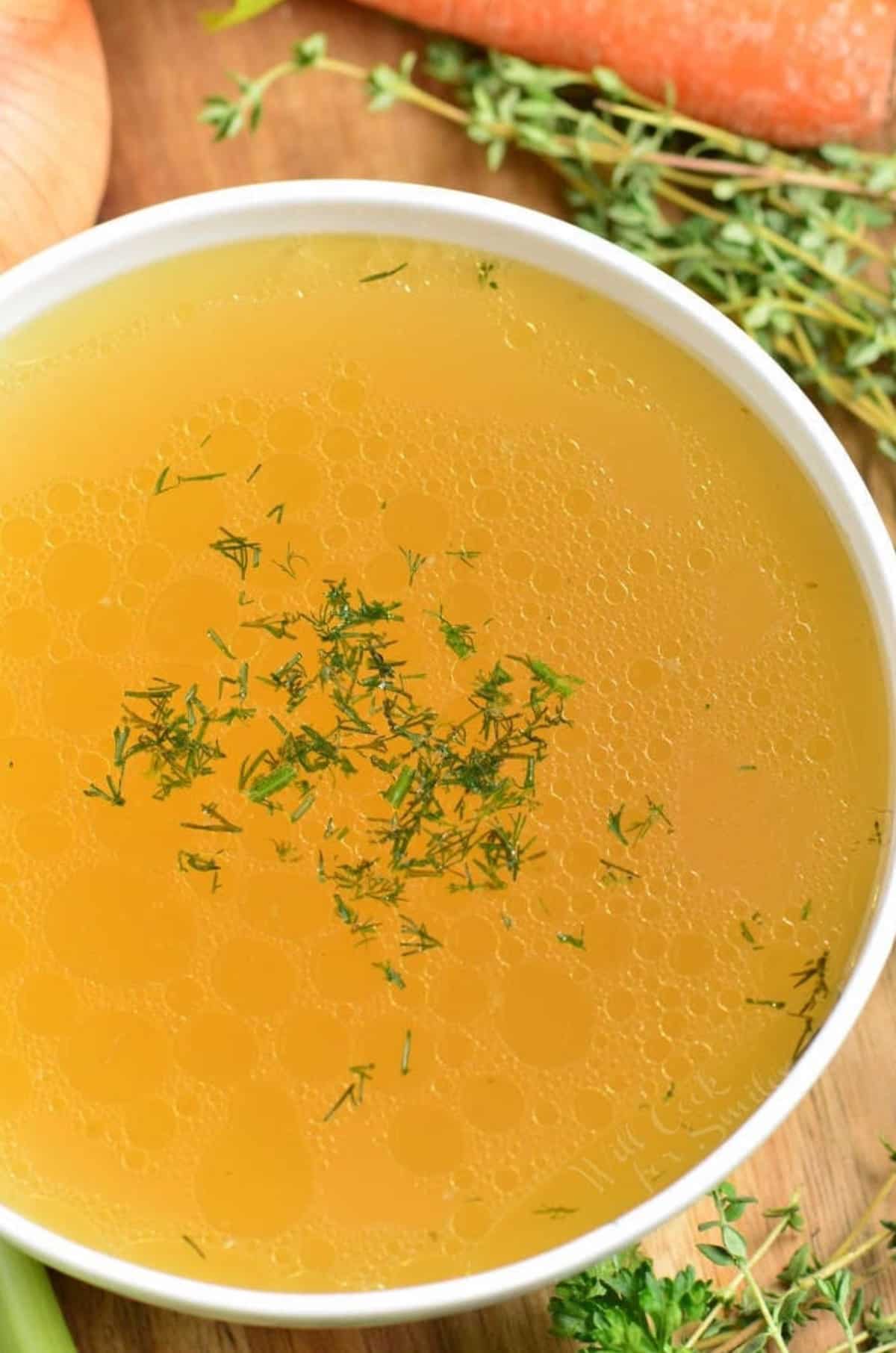 bowl of chicken stalk with herbs on top as garnish.