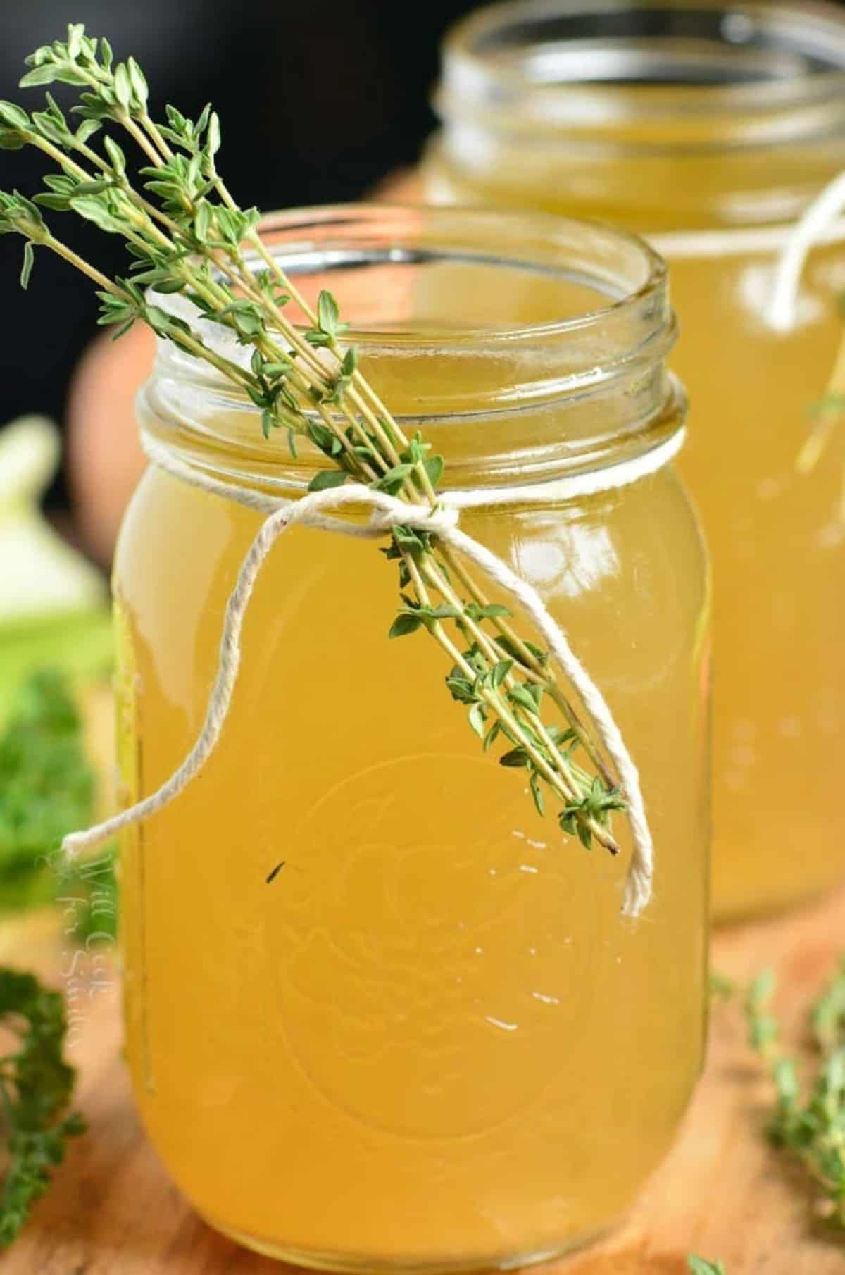 chicken stock in a mason jar with thyme tied to the jar with twine.