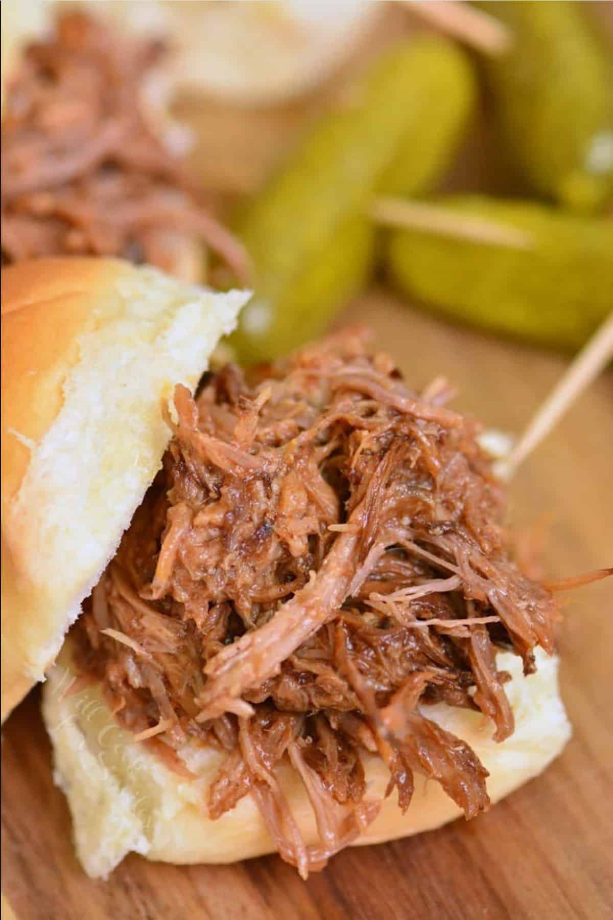 bbq pulled pork on a slider bun on a wood cutting board.