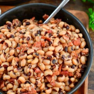 black eyed peas in a bowl with a fork in it on a wood surface.