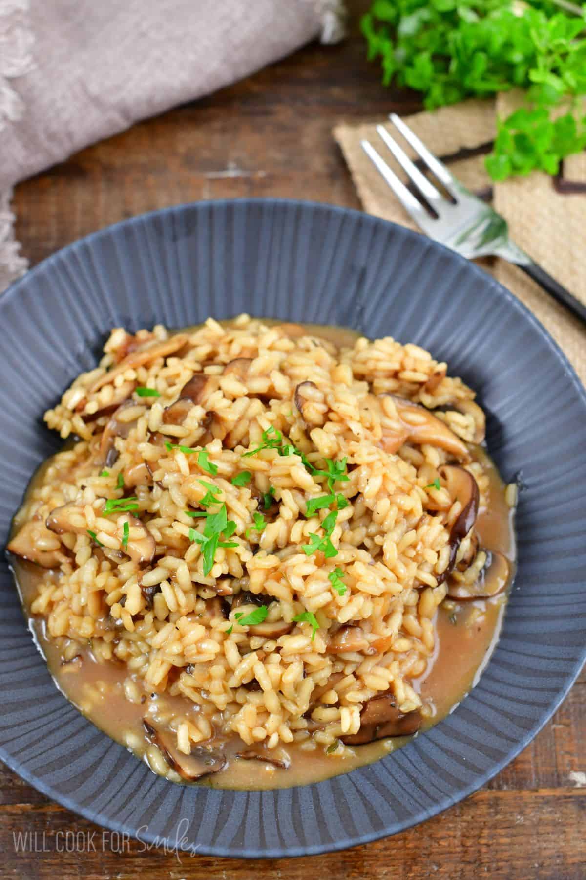 risotto in a bowl with parsley as garnish sitting on wood surface.