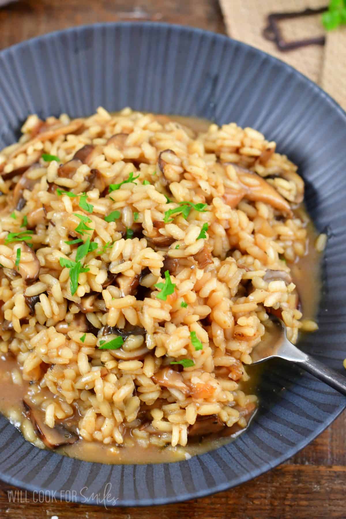 mushroom risotto in a bowl with a fork scooping some up.