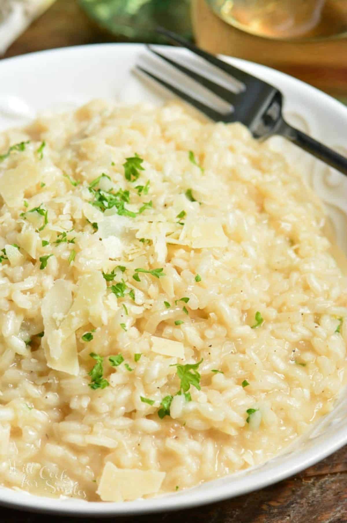 risotto in a bowl with cheese and parsley on top with a fork to the side.