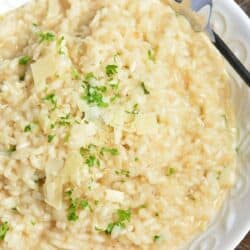 parmesan risotto in a white bowl with a fork to the side.