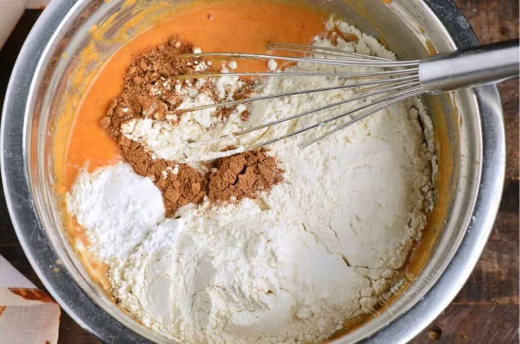 ingredients for pumpkin pan cakes in a bowl with a whisk.