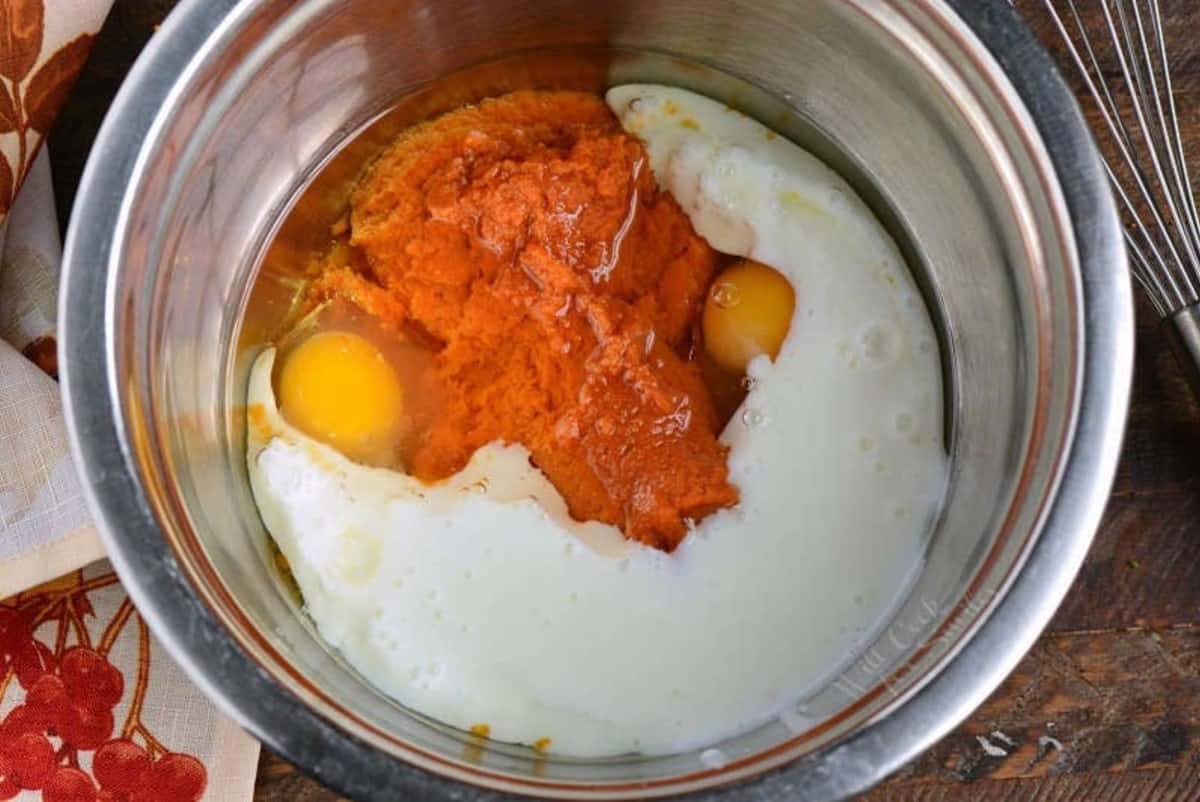 wet ingredients for pumpkin pancakes in a bowl on a wood surface.