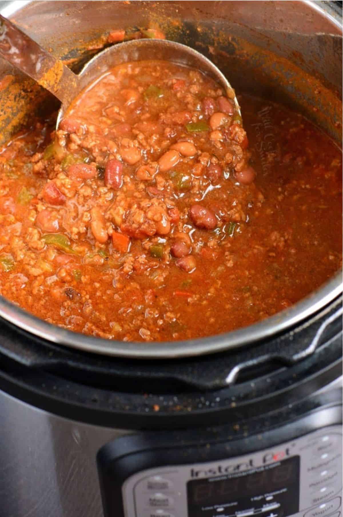 Chili in the instant pot with a ladle scooping some up.