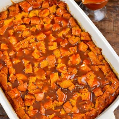 Pumpkin bread pudding with caramel over the top in a baking dish.
