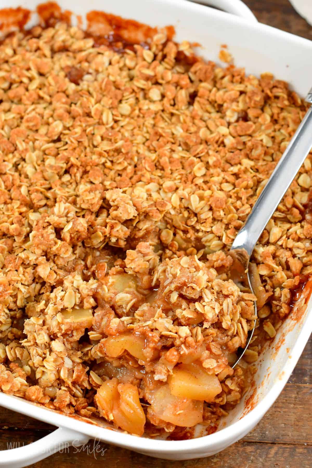 apple crisp in a baking pan with a spoon with a scoop on it.