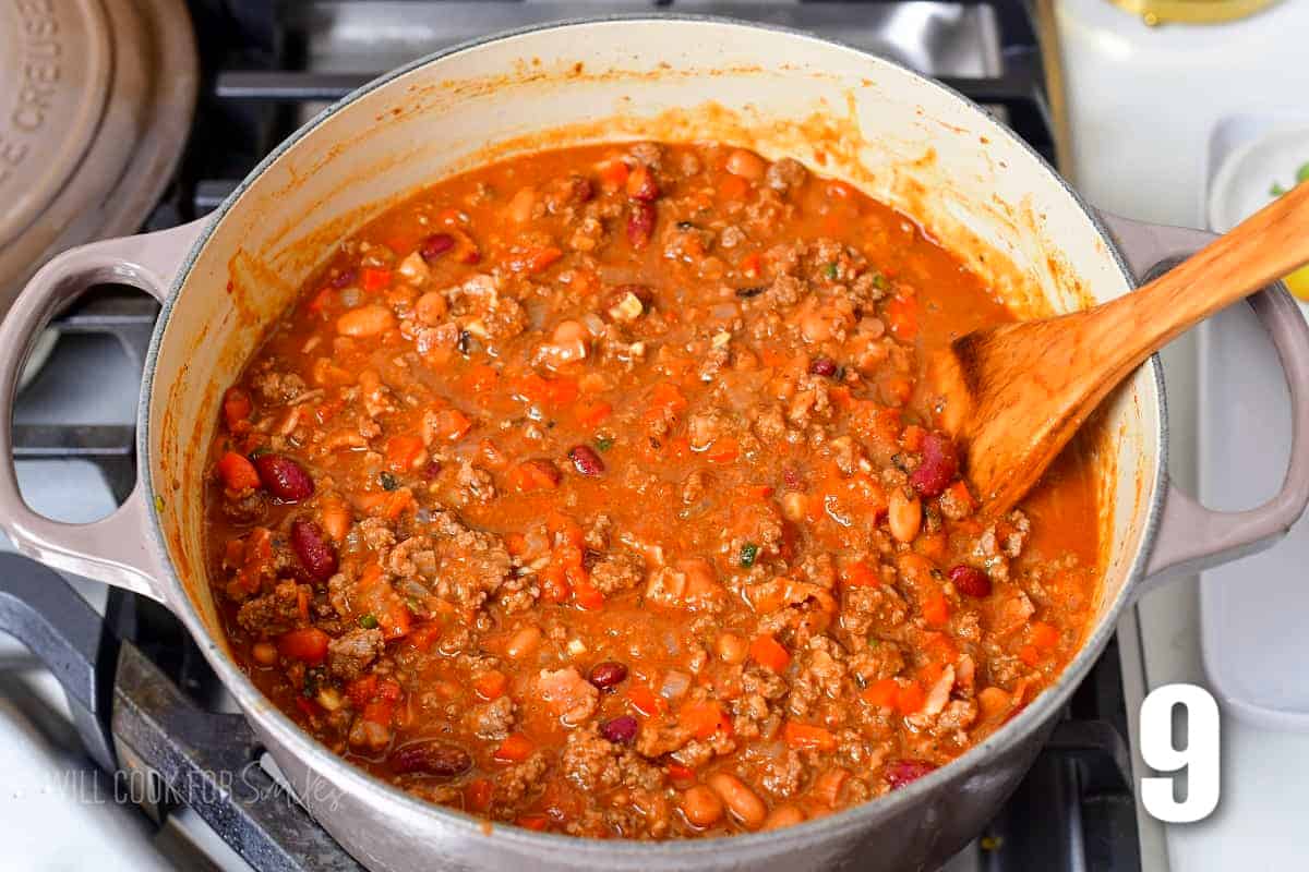 a large pot with chili and a ladle cooking on the stove.