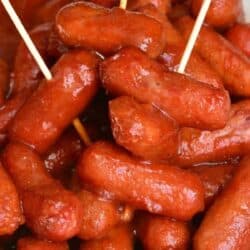 BBQ smokies in a bowl with 3 toothpicks in them and a wicker placemat.