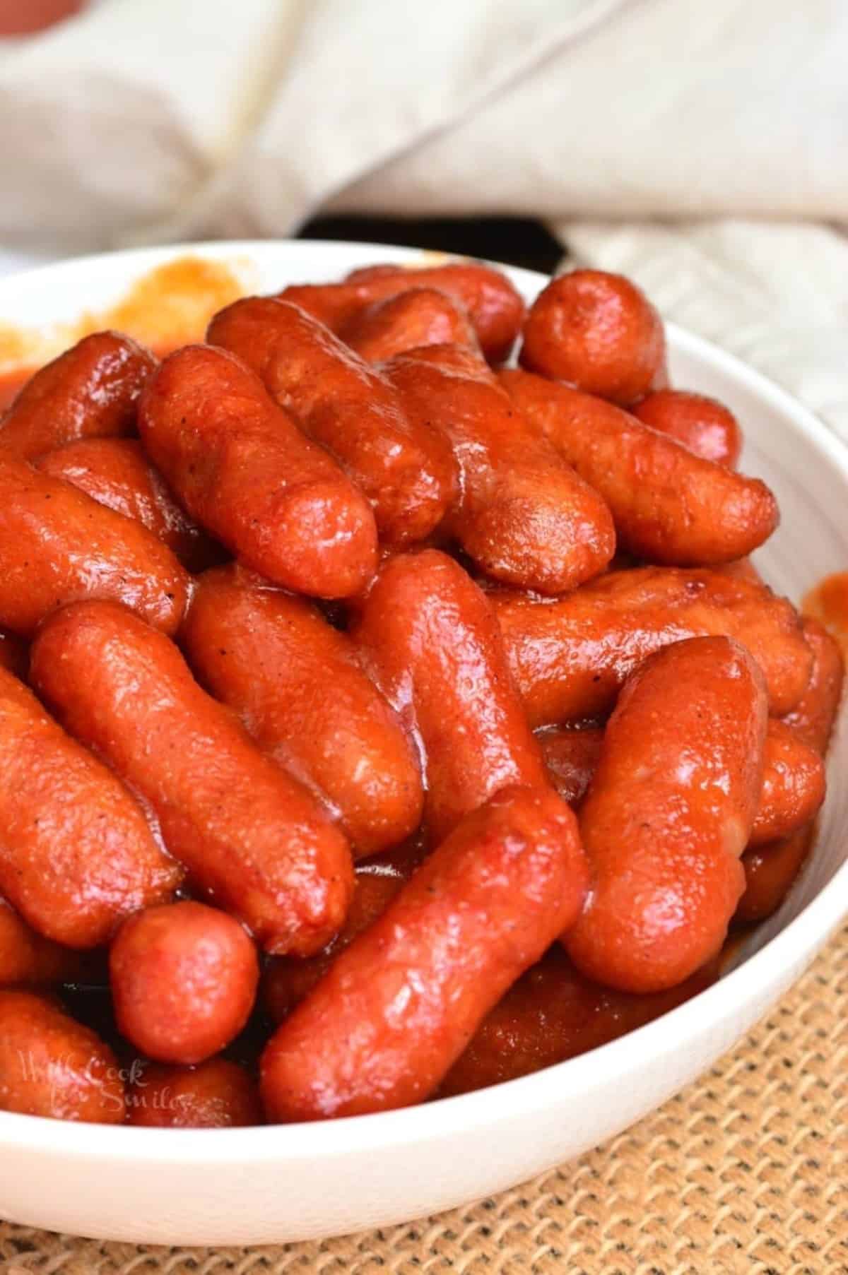 BBQ little smokies in a bowl on a wicker placemat.