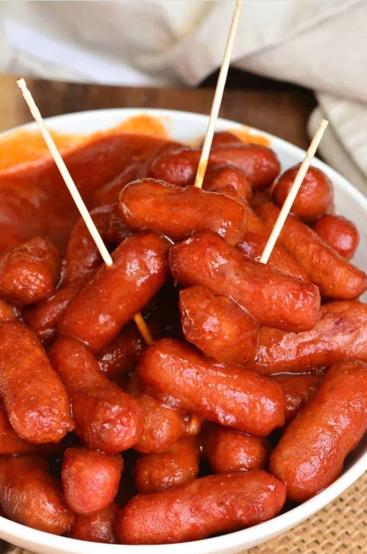 BBQ little smokies in a bowl with three toothpicks in them.