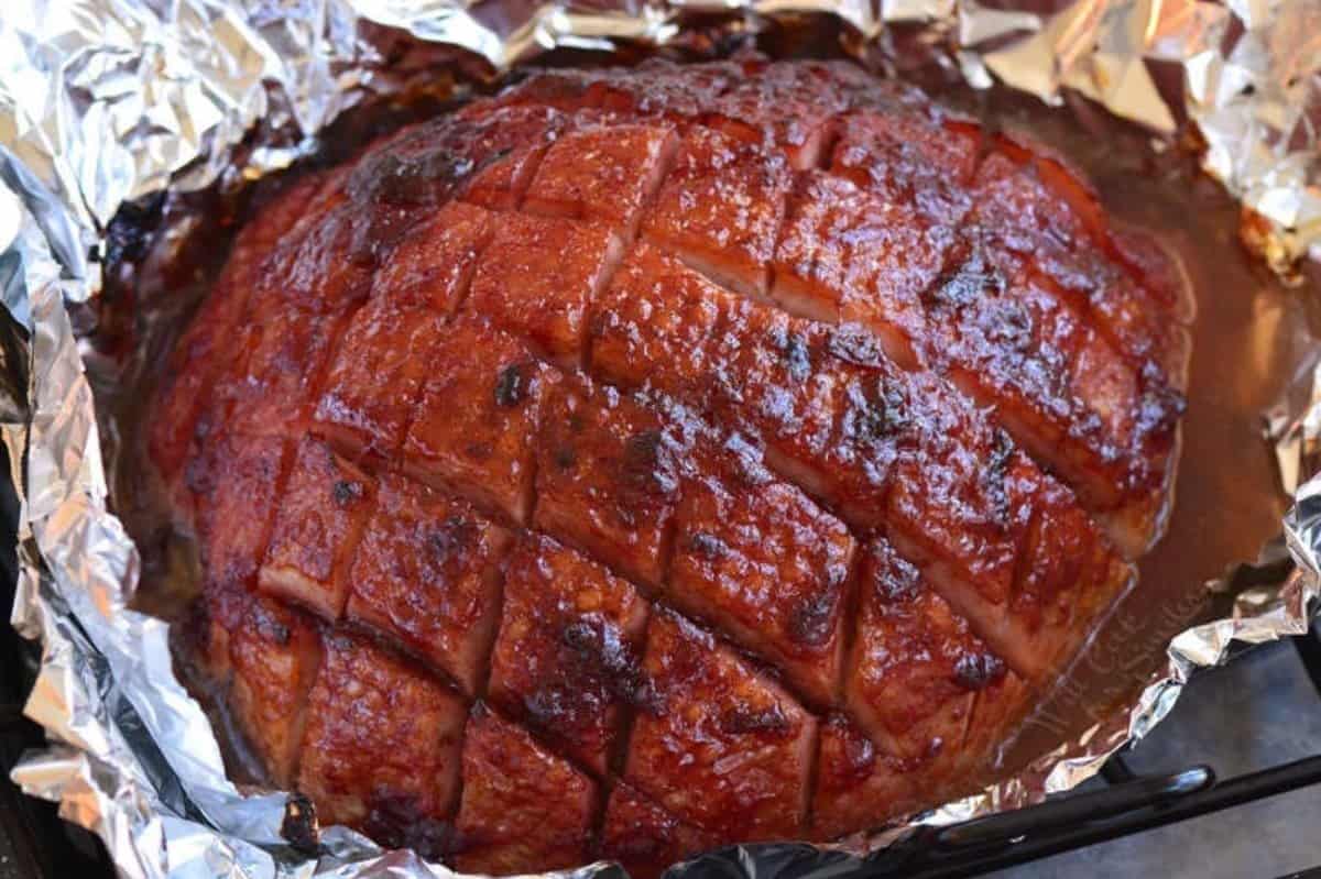 baked ham with cherry glaze wrapped in tin foil.