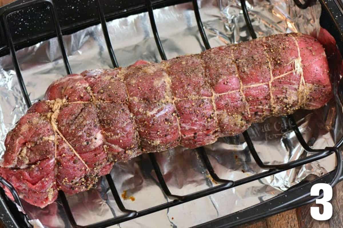tied and seasoned beef tenderloin on a rack in a roasting pan.