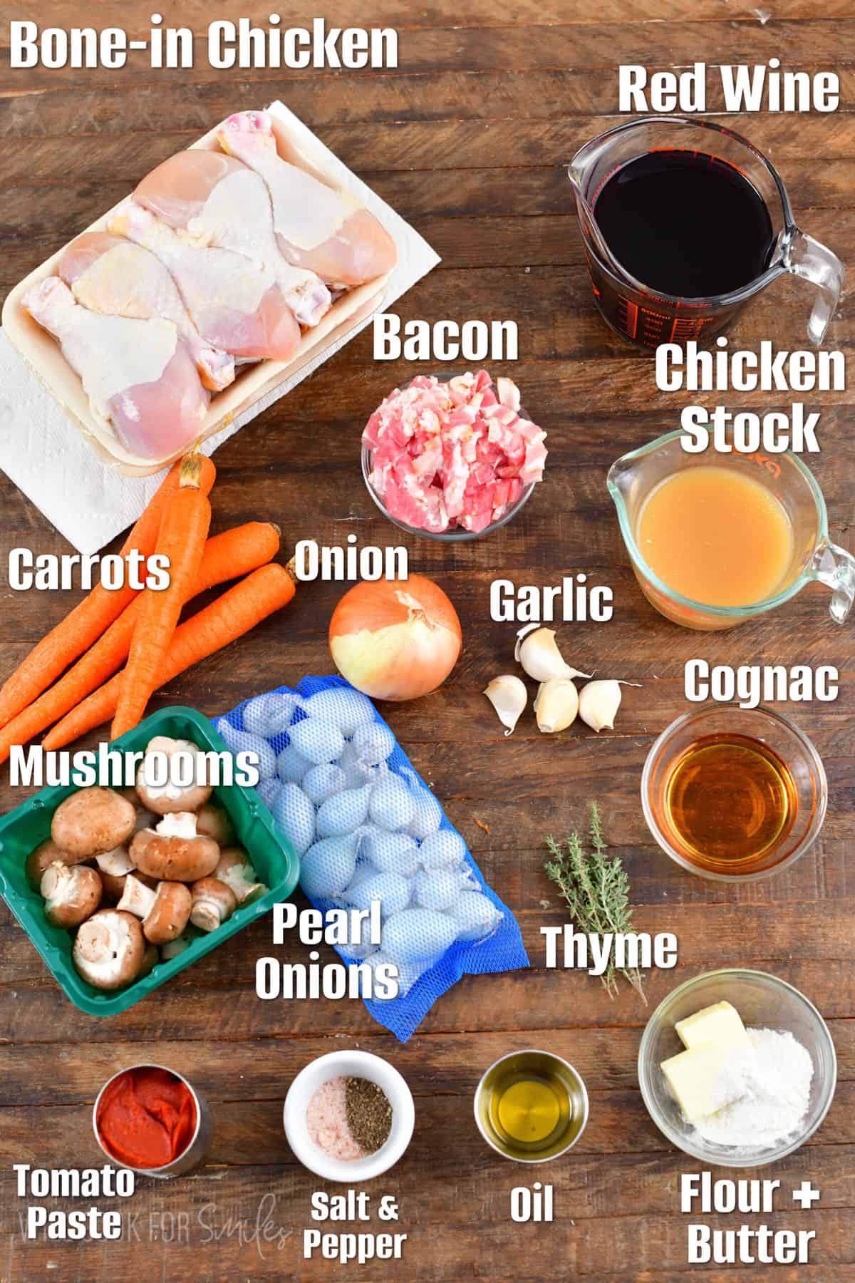 labeled ingredients for coq au vin on a wood surface.