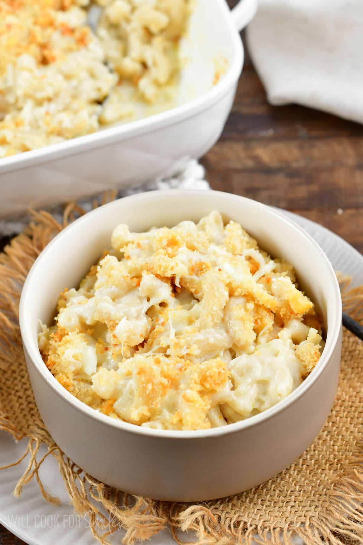 a bowl of mac and cheese with burlap under it and a white plate.