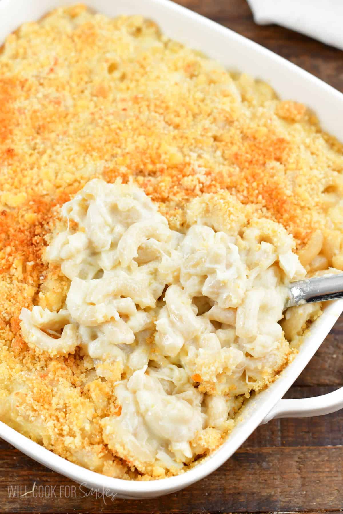 Crab mac and cheese in a baking dish with a scoop taken out.